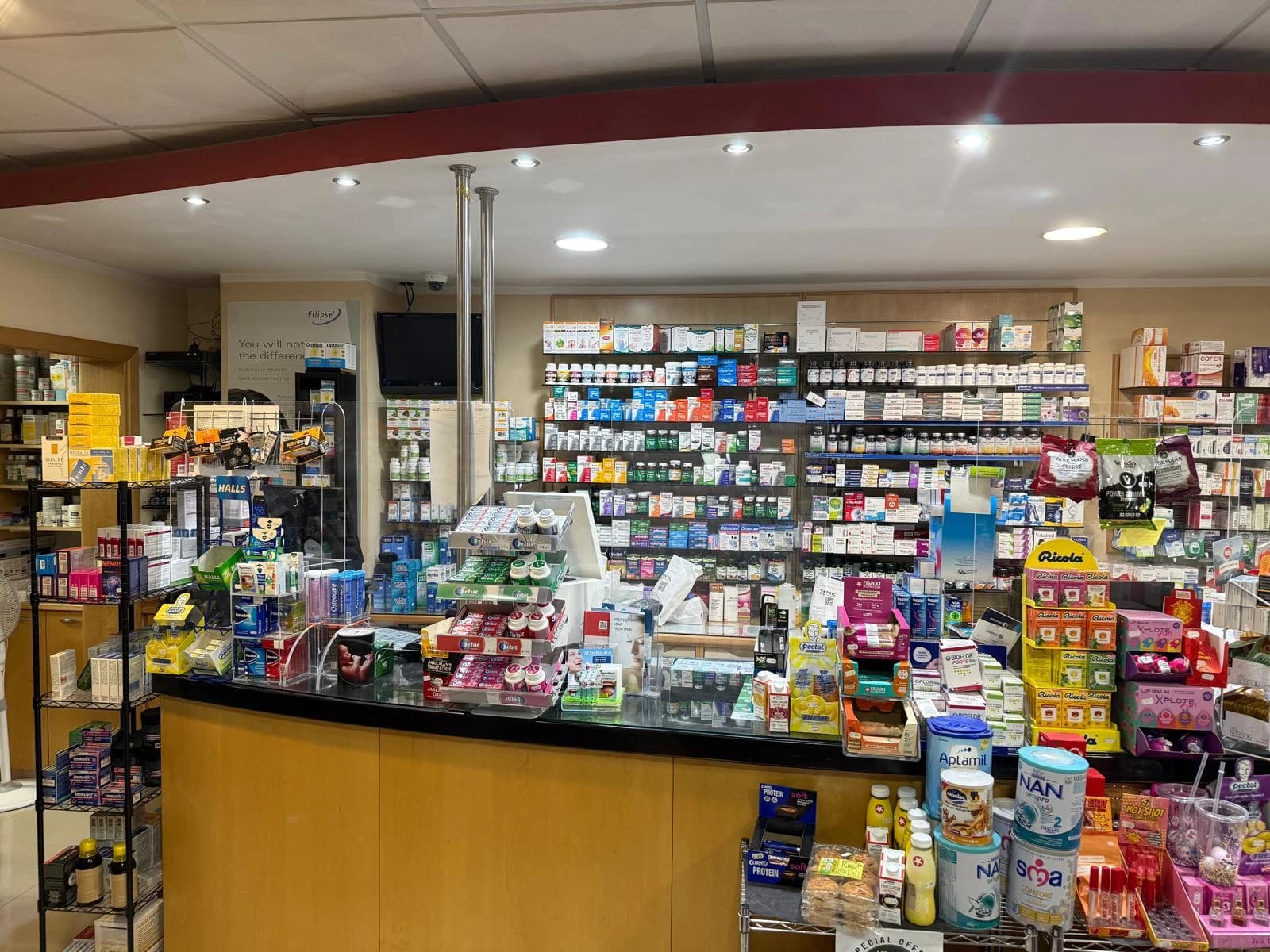 The Gozo Chemists dispensing counter, backed by a full wall of medicines and supplements.