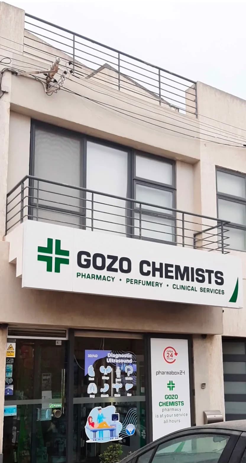 The Gozo Chemists shopfront on Mgarr Road, Xewkija, with its green cross sign reading pharmacy, perfumery and clinical services.